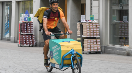 Velokurier in St.Gallen auf einem Cargobike, das mit viaVelo angeschrieben ist.